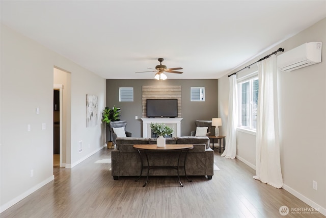 living room featuring a ceiling fan, wood finished floors, baseboards, a wall mounted AC, and a fireplace