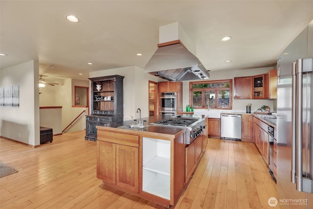 kitchen featuring stainless steel appliances, light wood finished floors, a sink, and island range hood