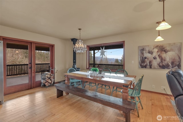 dining area with baseboards, french doors, light wood-type flooring, and a healthy amount of sunlight