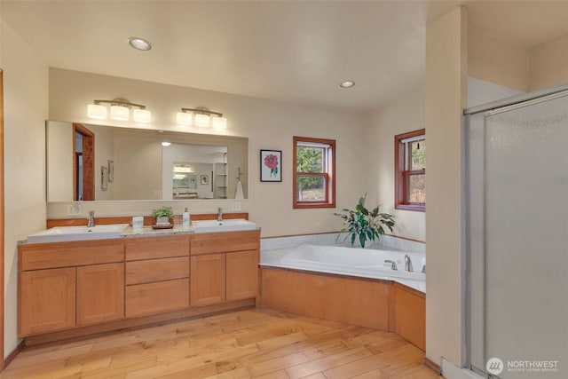 full bath featuring a garden tub, a sink, a shower stall, and wood finished floors