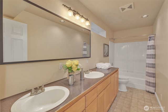 full bathroom with toilet, double vanity, visible vents, and a sink