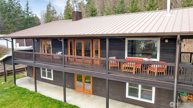 back of house with metal roof, french doors, a standing seam roof, and a chimney