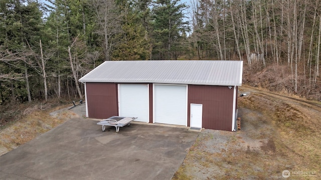 detached garage with a view of trees