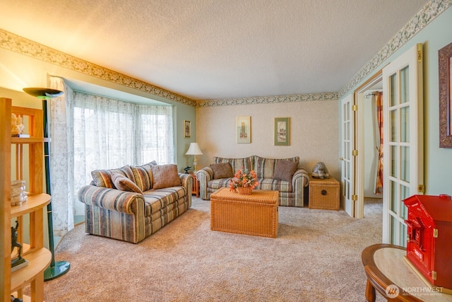 carpeted living area with french doors, a textured ceiling, and wallpapered walls