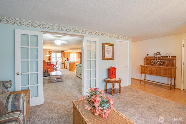 living area with light carpet, a textured ceiling, and french doors