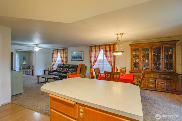 kitchen featuring light colored carpet, open floor plan, light countertops, light wood-type flooring, and pendant lighting