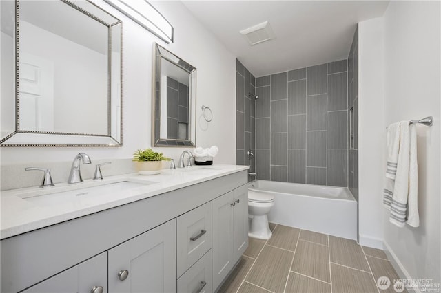 bathroom with shower / bath combination, a sink, toilet, and double vanity