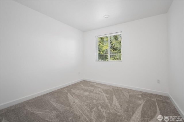 carpeted spare room featuring baseboards