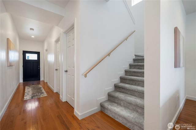 entryway featuring stairs, hardwood / wood-style floors, and baseboards