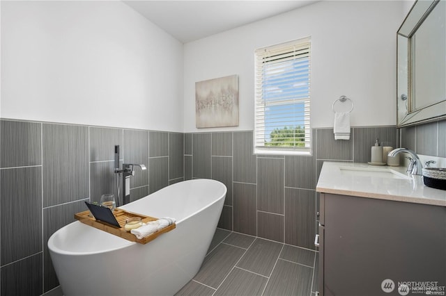 full bathroom featuring a freestanding tub, wainscoting, tile walls, and vanity