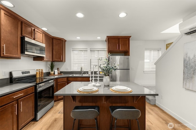 kitchen with stainless steel appliances, a sink, a center island, and a kitchen breakfast bar