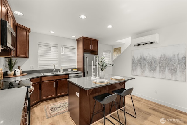 kitchen featuring a breakfast bar, a center island, stainless steel appliances, a sink, and a wall mounted AC