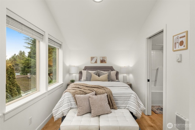 bedroom with light wood-style floors, vaulted ceiling, and baseboards