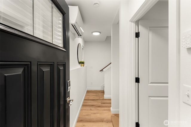 stairway featuring baseboards, an AC wall unit, and wood finished floors