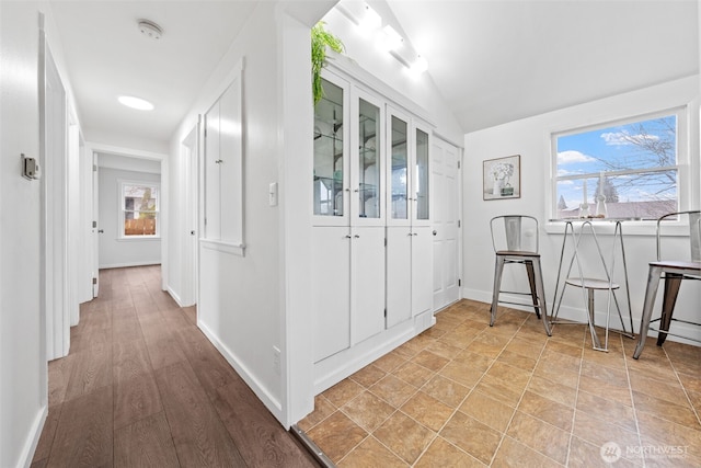 corridor featuring baseboards and vaulted ceiling