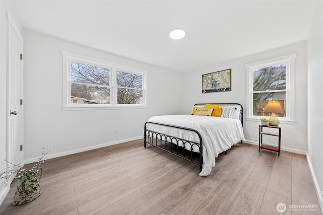 bedroom with light wood finished floors, multiple windows, and baseboards