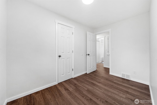 unfurnished bedroom with visible vents, dark wood finished floors, and baseboards