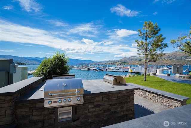 view of patio / terrace featuring exterior kitchen, area for grilling, and a water and mountain view