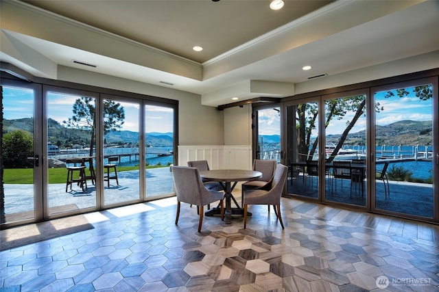 dining space with a tray ceiling, visible vents, a mountain view, and crown molding