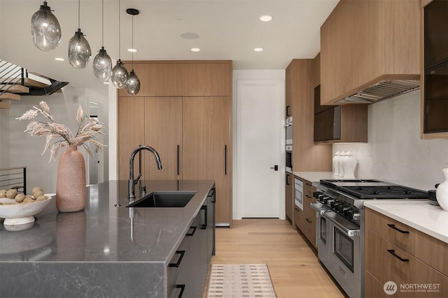 kitchen with premium range hood, light wood finished floors, range with two ovens, a sink, and modern cabinets