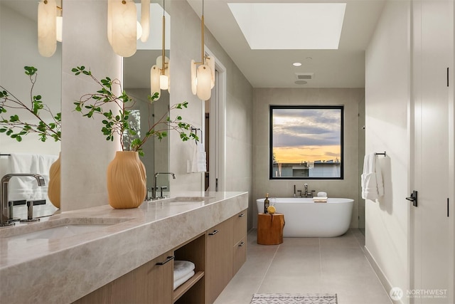 full bath featuring double vanity, a soaking tub, a skylight, and a sink