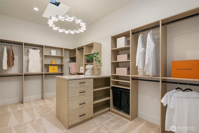 spacious closet featuring a skylight, light colored carpet, and a chandelier