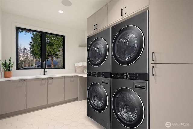 laundry room featuring stacked washer and dryer, a sink, recessed lighting, cabinet space, and light tile patterned floors