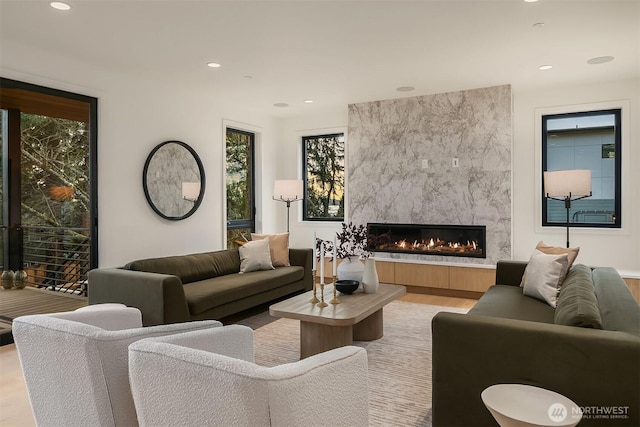 living area featuring recessed lighting, a fireplace, and light wood finished floors