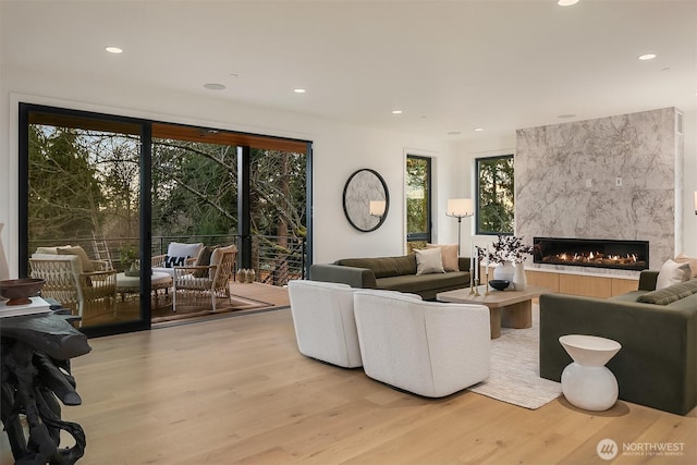 living room featuring a high end fireplace, light wood-type flooring, and a wealth of natural light