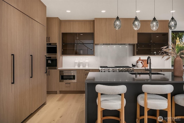 kitchen featuring a breakfast bar, double oven, modern cabinets, and a sink