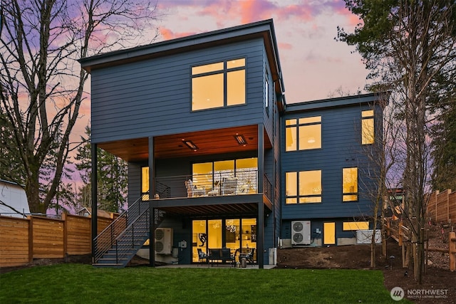 back of property at dusk featuring stairway, a yard, a patio area, and fence