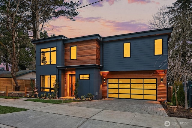 contemporary home featuring an attached garage and decorative driveway