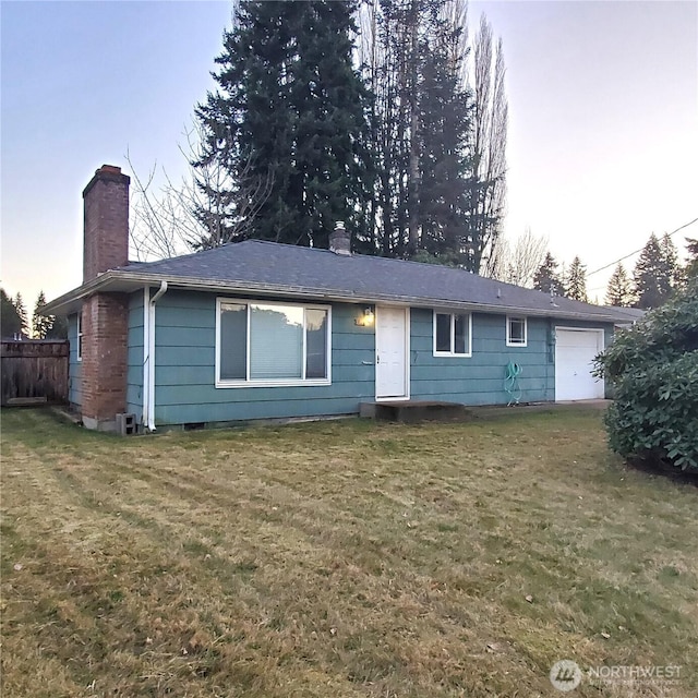 view of front facade with a garage, a chimney, and a front yard