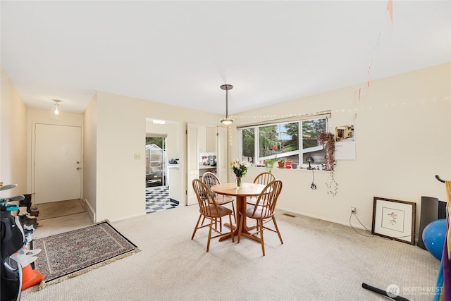 dining room featuring light carpet and baseboards