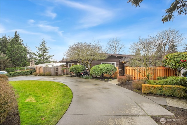 single story home with driveway, a fenced front yard, and a front yard