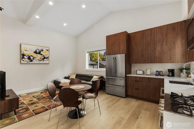 kitchen featuring modern cabinets, high end fridge, vaulted ceiling, light countertops, and a sink