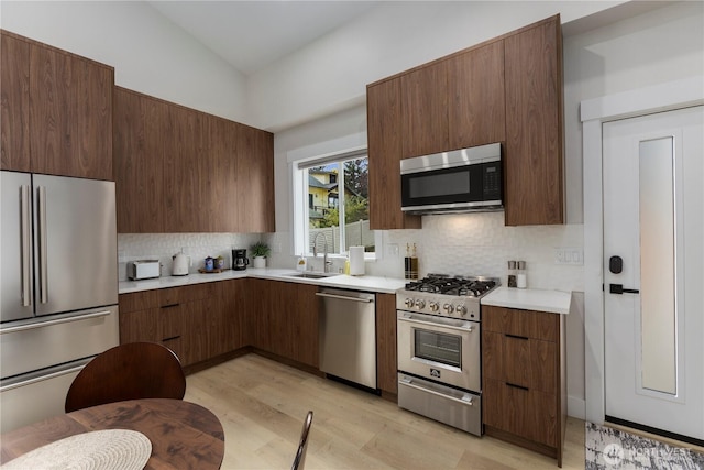 kitchen featuring modern cabinets, decorative backsplash, stainless steel appliances, and light countertops