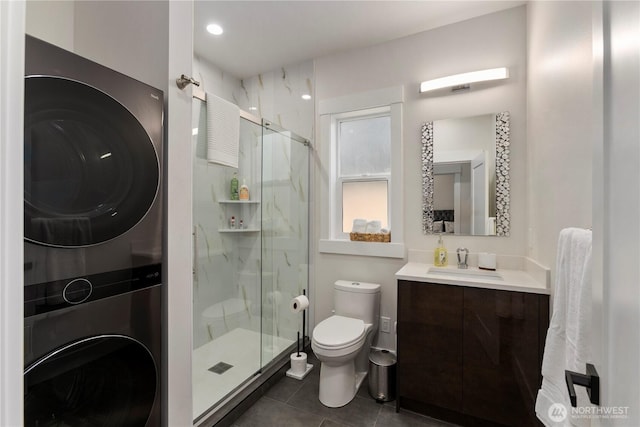 bathroom with stacked washer / dryer, a marble finish shower, vanity, and toilet