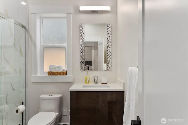 full bath featuring a marble finish shower, vanity, and toilet