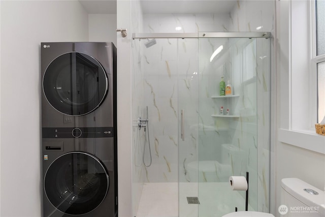 bathroom with toilet, a marble finish shower, and stacked washer / drying machine