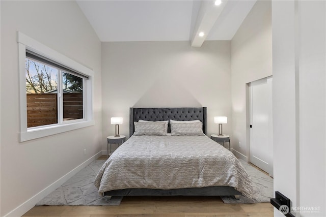 bedroom with light wood-style flooring, baseboards, and beamed ceiling