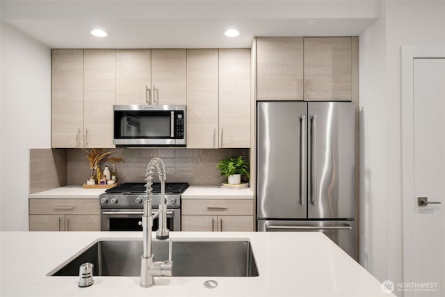 kitchen featuring premium appliances, light countertops, decorative backsplash, light brown cabinetry, and modern cabinets