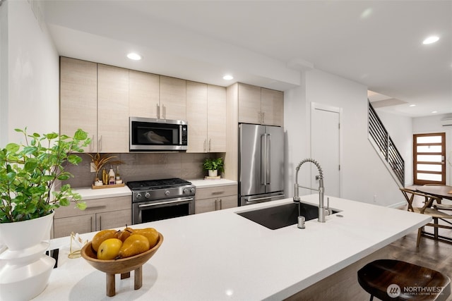 kitchen featuring tasteful backsplash, high end appliances, light countertops, a sink, and recessed lighting