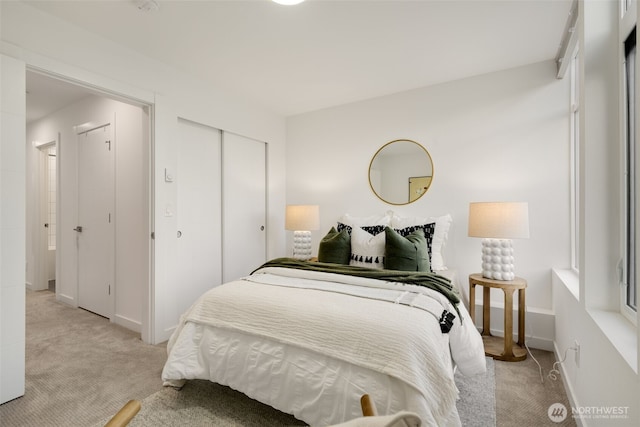 bedroom featuring light carpet, a closet, and baseboards