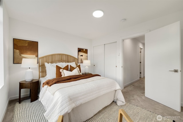 bedroom with a closet, light colored carpet, and baseboards