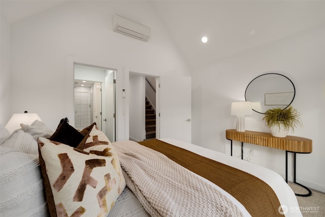 bedroom featuring a wall unit AC, high vaulted ceiling, connected bathroom, and recessed lighting