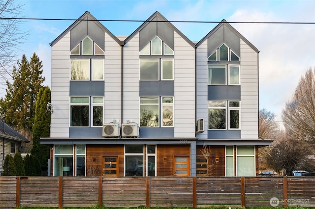 rear view of property with a fenced front yard and ac unit