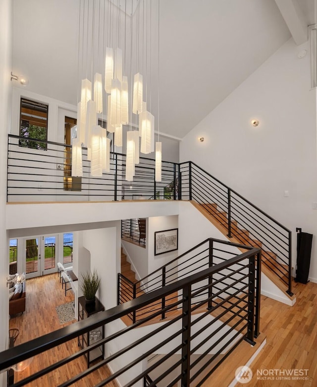 stairs with wood finished floors and a towering ceiling