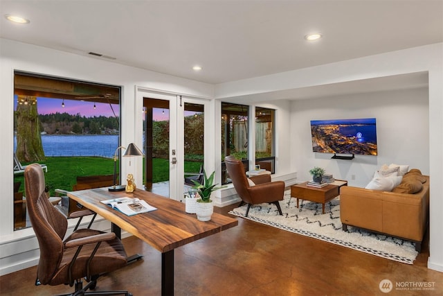 office area with concrete floors, a water view, visible vents, and recessed lighting