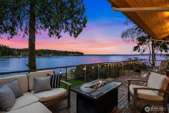 wooden deck with a water view and an outdoor living space with a fire pit